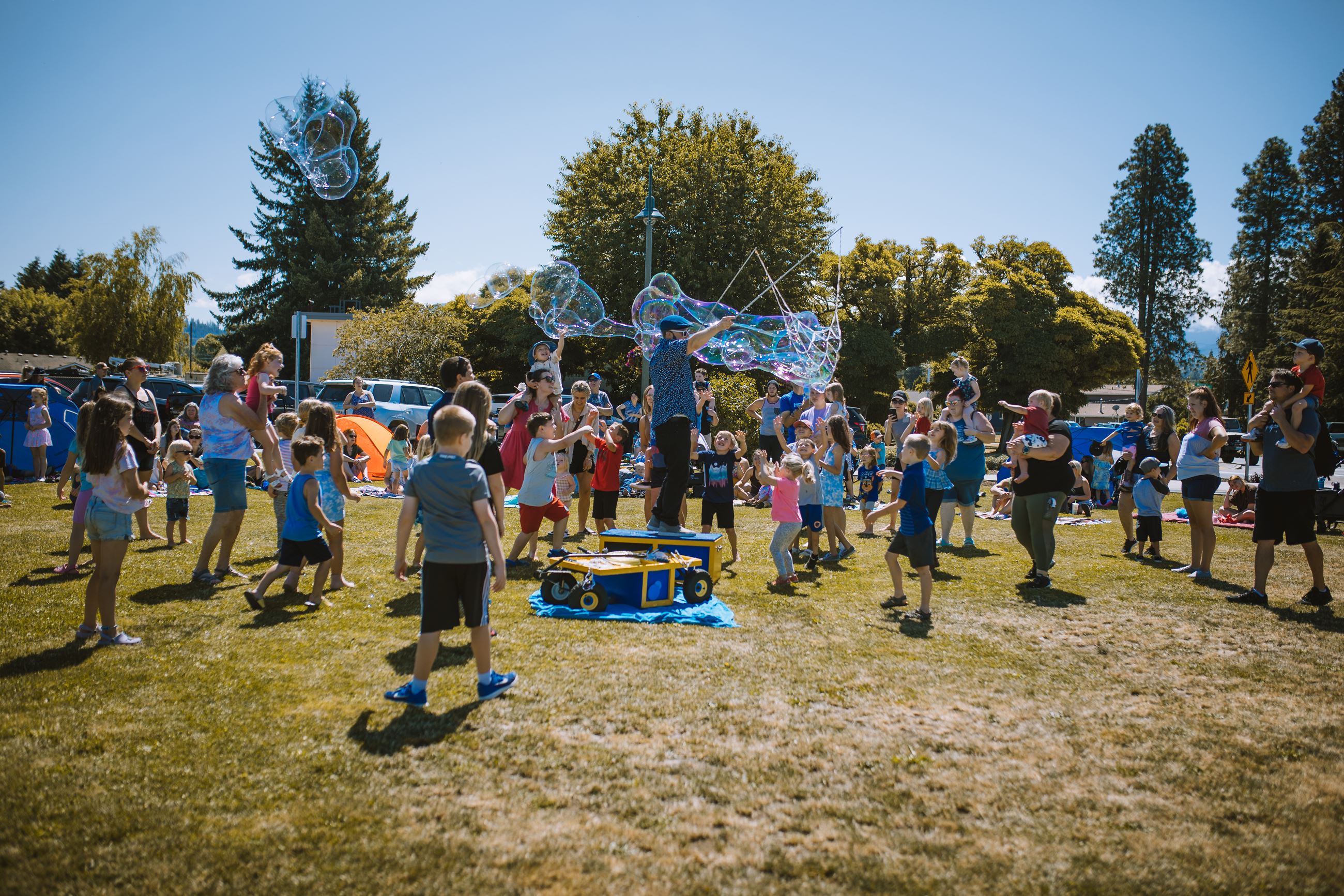 Person making giant bubbles for kids at outdoor event